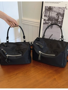 Durable black nylon crossbody bags in two sizes with silver zippers on a wooden table