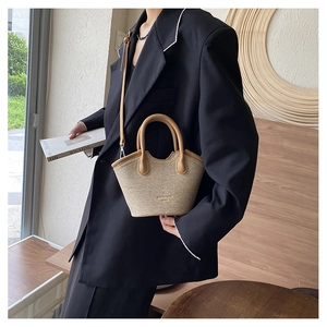 Detail of hand-woven bucket bag with beige texture and contrasting brown leather trim