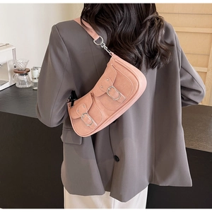 Rosafarbene Schultertasche aus Wildleder mit Schnallentaschen auf grauem Anzug getragen