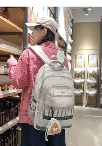 Détail du sac à dos blanc cassé multi-compartiments avec un petit porte-monnaie pizza
