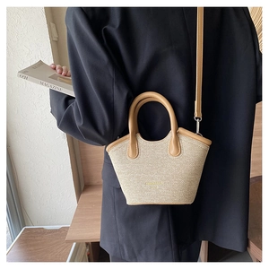 Detail view of woven bucket bag with khaki handles and adjustable shoulder strap