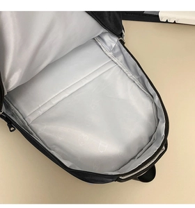 Interior view of black backpack showing silver lining with cartoon patterns and laptop sleeve