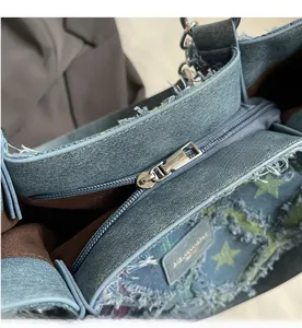 Détail de la fermeture éclair argentée et du motif d'étoiles sur ce sac en jean