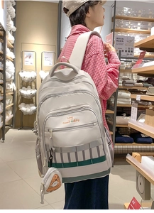 Détail d'un sac à dos beige grande capacité avec pendentif pizza et imprimé Have a Good day
