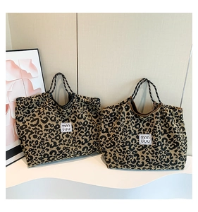 Macro detail of leopard print woven tote bags with contrast handles and logo labels