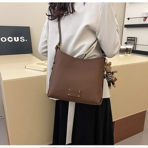 Detail of brown litchi pattern leather bucket bag with a cute rabbit doll charm