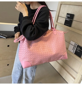 Detail of pink woven tote bag showing cross-weave texture and reinforced leather corners