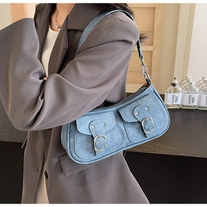 Detail der blauen Denim-Umhängetasche mit Doppeltaschen und silbernen Schnallen am Modell