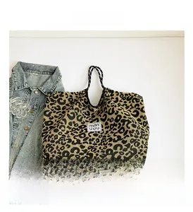 Macro shot of leopard print canvas tote bag with textured fabric and logo label detail