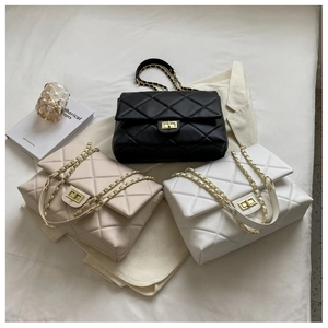 Close-up of quilted diamond pattern bags in black and beige with gold metal chain straps