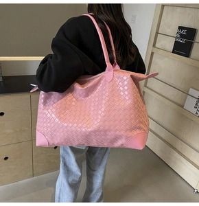 Detailed view of pink woven tote bag showing durable leather base and shoulder strap