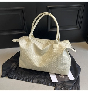 Detailed view of the cream woven tote bag showing the texture and metal zipper closure