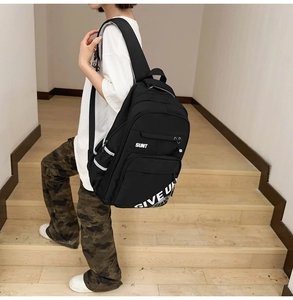 Macro detail of high-capacity black backpack with white SUNT lettering and padded straps