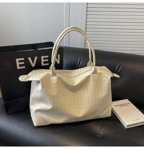 Detail of the woven leather texture and double handles on a creamy white large tote bag