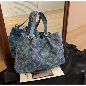 Détail du sac cabas en denim bleu avec motifs d'étoiles colorées et bords à franges