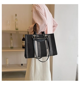 Detail van gestreepte canvas shopper met leren handvatten en metalen rits
