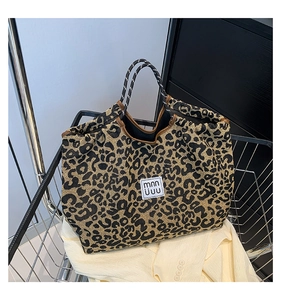 Detail of leopard print tote bag with woven fabric and black-and-white rope handles