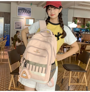 Sac à dos rose pour étudiante avec fermetures éclair et pendentif pizza dans un café lumineux