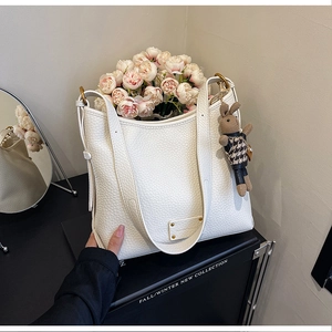 Close-up of white pebble leather bucket bag with gold hardware and rabbit charm