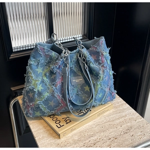 Détail du cabas en denim à imprimé étoiles avec bords effilochés et poignée en chaîne