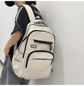 Detail of ergonomic padded straps and side pocket on this cream canvas student backpack