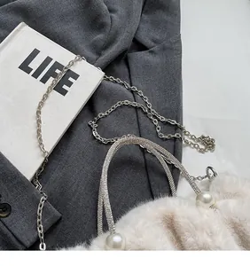 Detail van beige pluche cloud bag met parels, diamant handvat en kettingriem