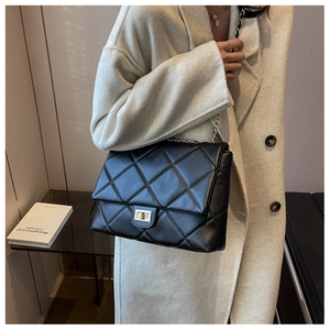 Classic black quilted shoulder bag with gold twist lock and chain strap on a model
