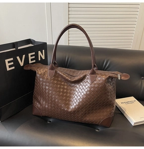 Macro detail of deep brown woven leather tote showing fine texture and corner reinforcement