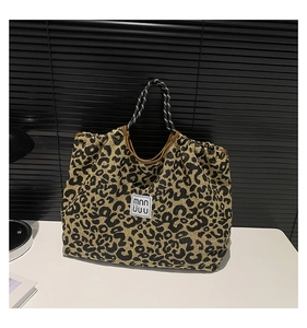 Close-up of leopard print canvas tote bag with woven handles and brand label patch