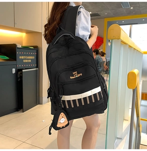 Détail du sac à dos scolaire noir à grande capacité avec imprimé sourire et breloque chat