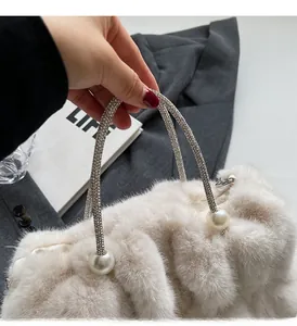 Detail van beige handtas van imitatiebont met handvat van strass-steentjes en parelaccenten