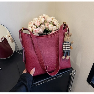 Detail of burgundy lychee leather bucket bag with gold logo and cute rabbit charm