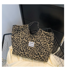 Close-up of leopard print tote bag with woven handles and minimalist logo patch