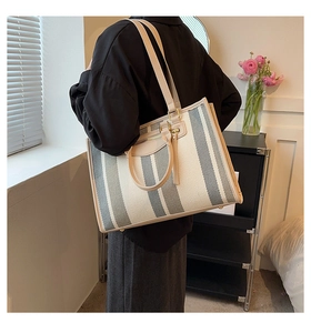 Detail van gestreepte canvas shopper met geweven textuur en goudkleurige hardware