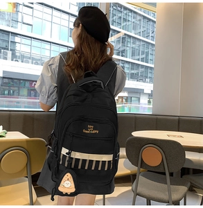Détail du sac à dos noir avec bande réfléchissante et porte-clé pizza au café