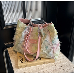 Gros plan du sac cabas en toile à motif d'étoiles avec franges et bandoulière chaîne