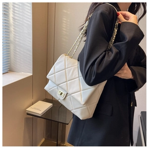 Detail of white quilted leather texture and gold metal twist-lock on a stylish shoulder bag