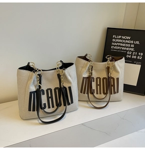 Detail view of canvas tote bags with bold letter prints and gold chain leather straps