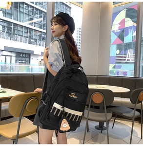 Détail d'un sac à dos noir avec broderie texte et petit pendentif en forme de pizza
