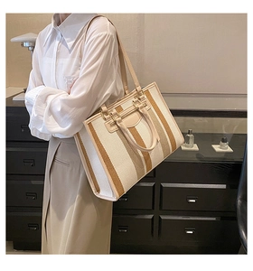 Model draagt een grote gestreepte canvas shopper met leren bies en brede schouderriem