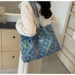 Détail du cabas en jean bleu avec patchs d'étoiles colorées et bandoulière chaîne