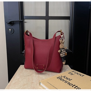 Close-up of wine red lychee grain leather bucket bag with a cute rabbit doll pendant