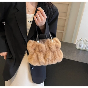 Detail van pluche faux fur cloud tas in camel met elegante parelaccenten op het handvat