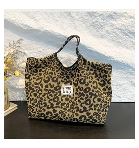 Detail of leopard print tote bag with woven rope handles and minimalist logo label