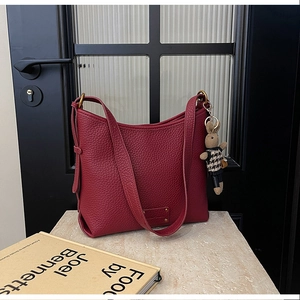 Detail of dark red lychee grain leather bucket bag featuring a cute knit bunny pendant