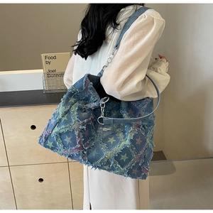 Détail du sac cabas en denim avec patchwork d'étoiles effilochées et chaîne métal