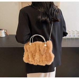 Bruine faux fur cloud bag met strass handvaten en parel accenten op een model