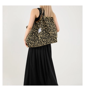 Detailed side view of the leopard print tote bag with a white brand label and fabric texture