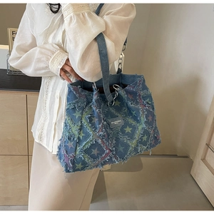 Détail du sac cabas en jean bicolore avec motifs d'étoiles et bords effilochés