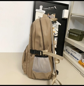 Detail view of khaki backpack featuring side mesh pocket and adjustable buckle strap
